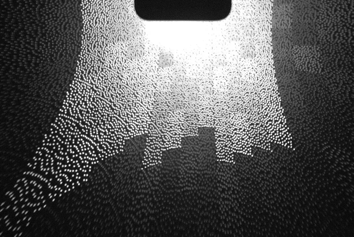 Infrared photograph of the thousands of tiny dots a phone's face sensor projects, forming a pattern of light on a dark background.