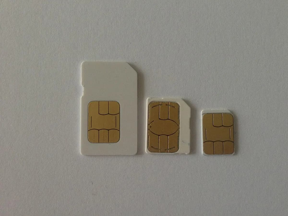 Three SIM cards of different sizes lying side by side on a white surface.